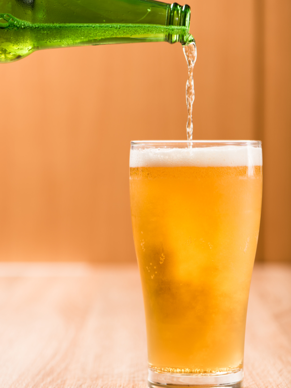 Pouring beer into glass on wood background